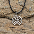 Silver spiral pendant on a black cord against a wooden background