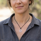 Woman wearing a necklace with a spiral pendant outdoors