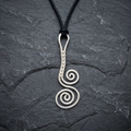Silver spiral pendant on a black cord against a dark stone background