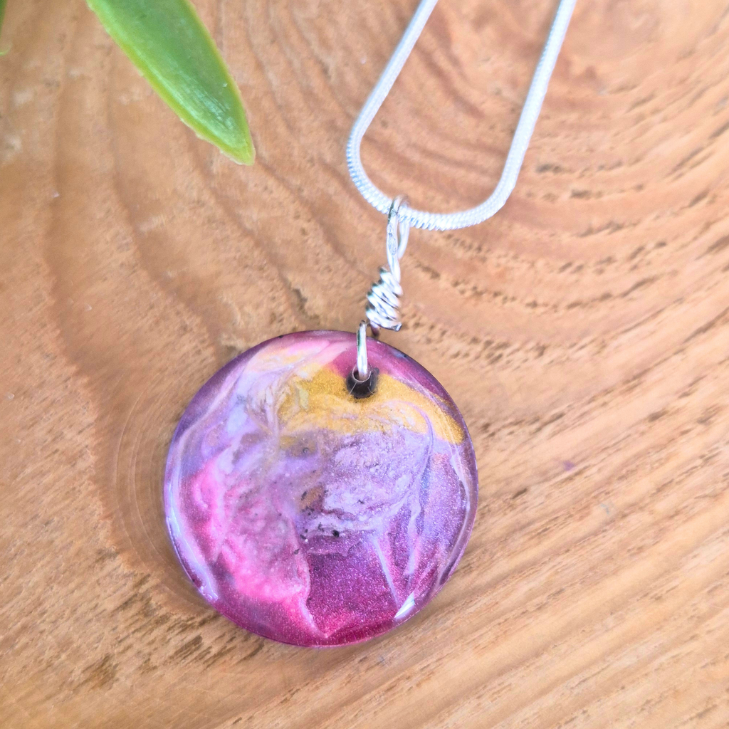 Necklace with a round, multicolored pendant on a wooden surface