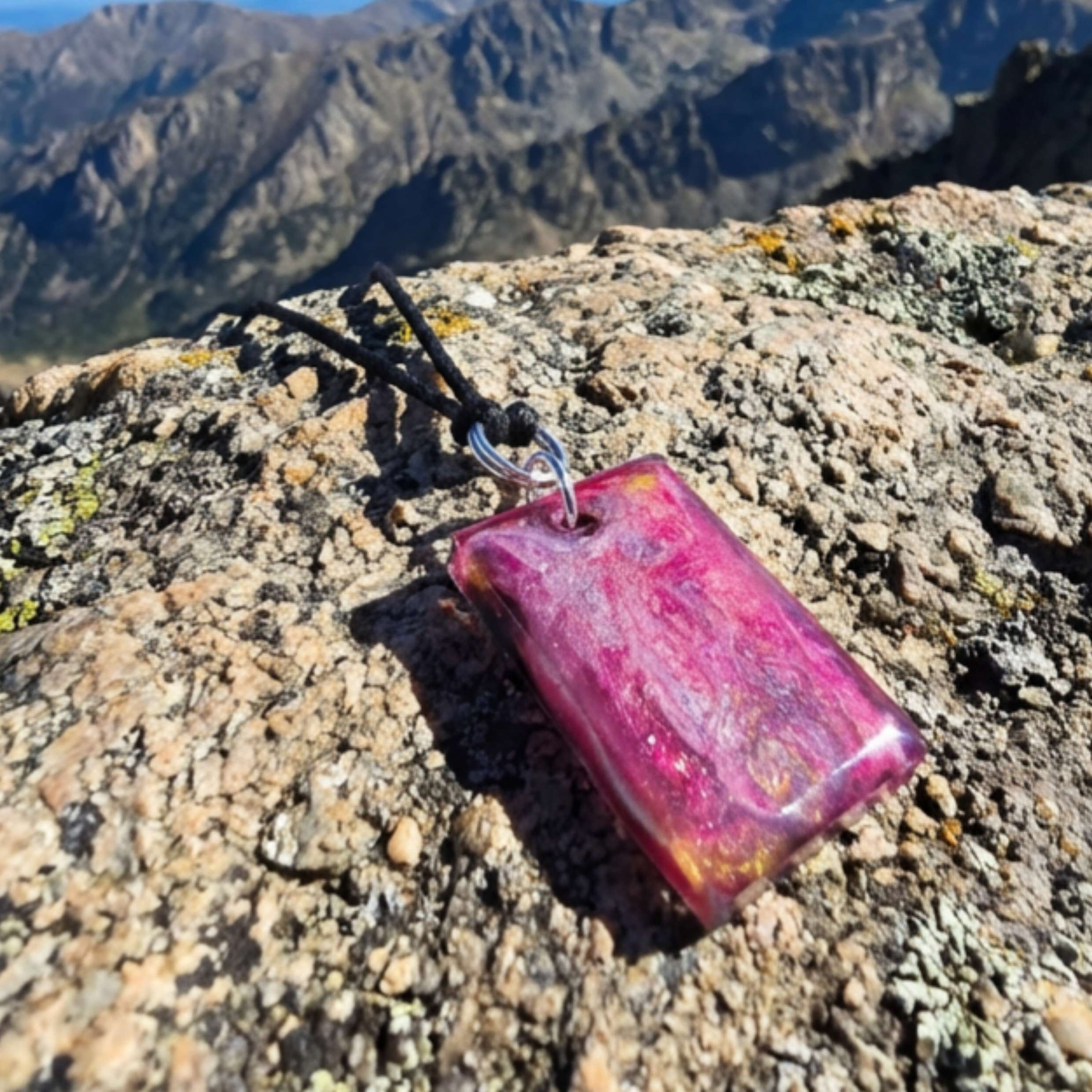 Pink gold and purple rectangle pendant on a mountain