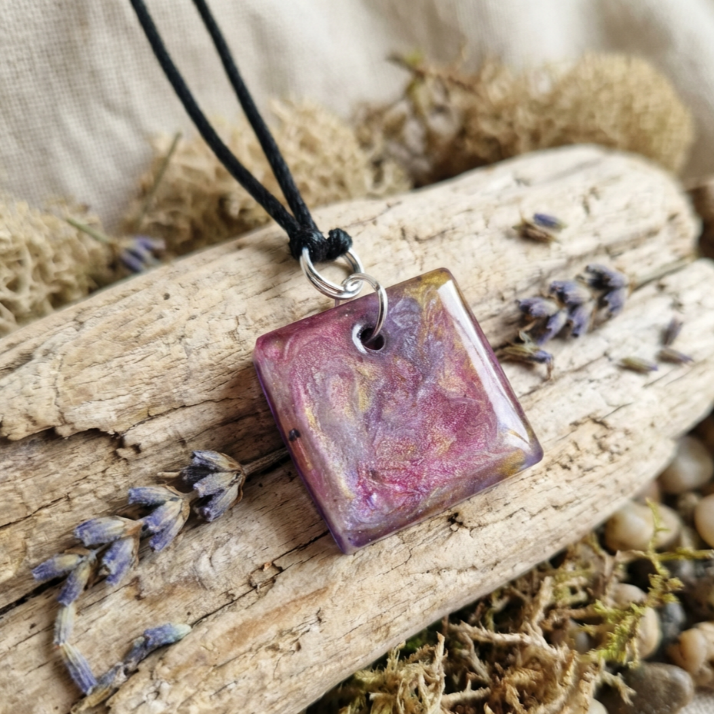 Necklace with a square pendant on a piece of wood with lavender flowers