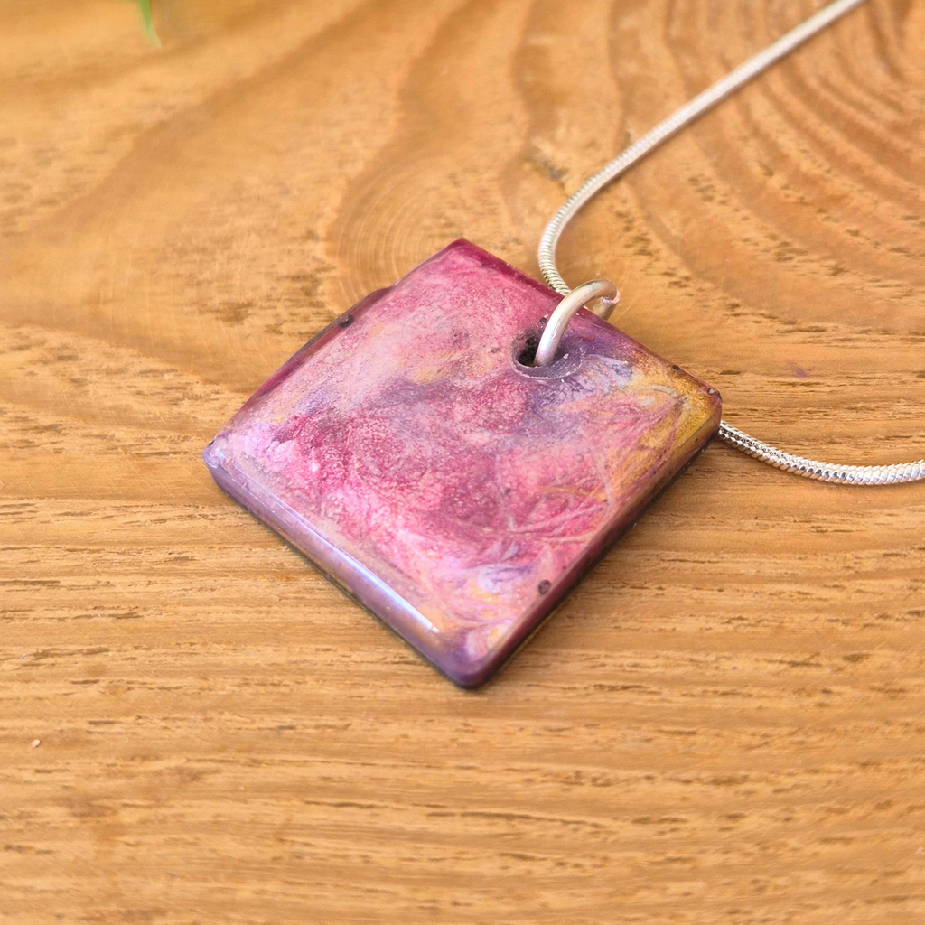 Square pendant with a pink and purple gradient on a wooden surface