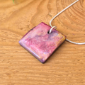 Square pendant with a pink and purple gradient on a wooden surface