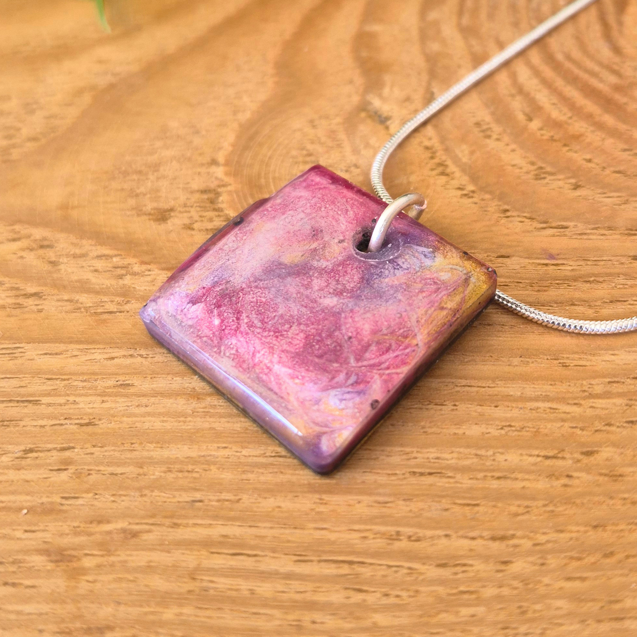 Square pendant with a pink and purple gradient on a wooden surface