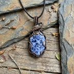 Necklace with a blue stone pendant on a stone surface