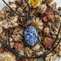 Copper pendant with blue speckled Sodalite gemstone on a bed of dried flowers