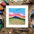 Colourful dot painting of Glastonbury Tor on a wooden surface with art supplies