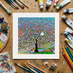 Colourful tree artwork on a wooden surface with art supplies