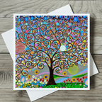 Colourful tree of life design on a card with a white envelope on a wooden surface
