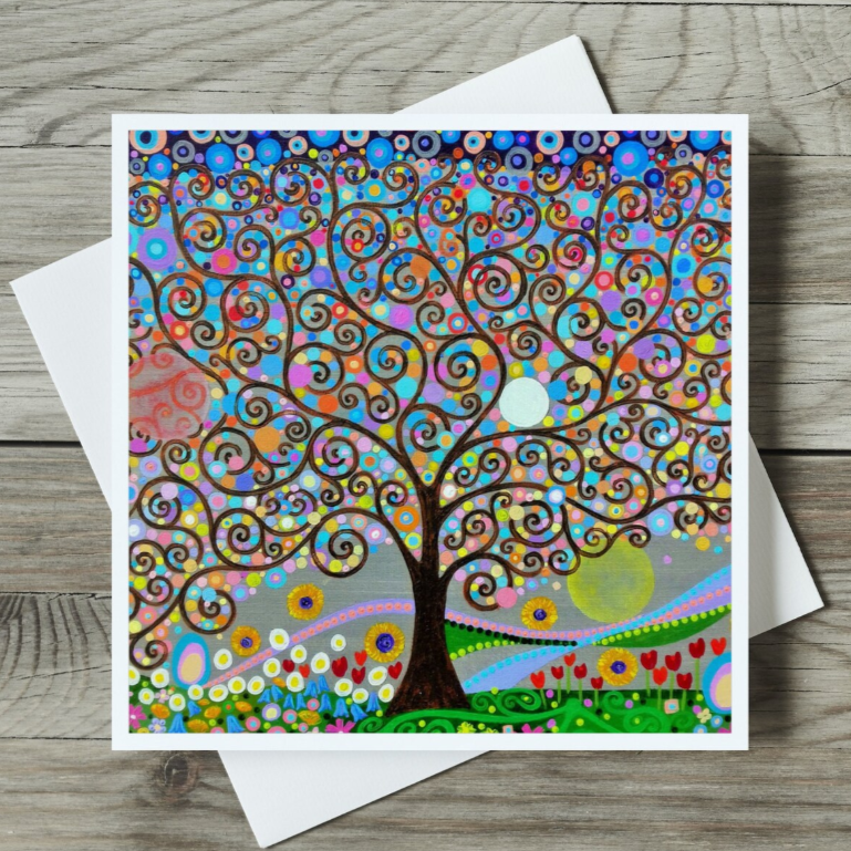 Colourful tree of life design on a card with a white envelope on a wooden surface