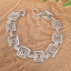 Silver bracelet with spiral designs on a wooden surface