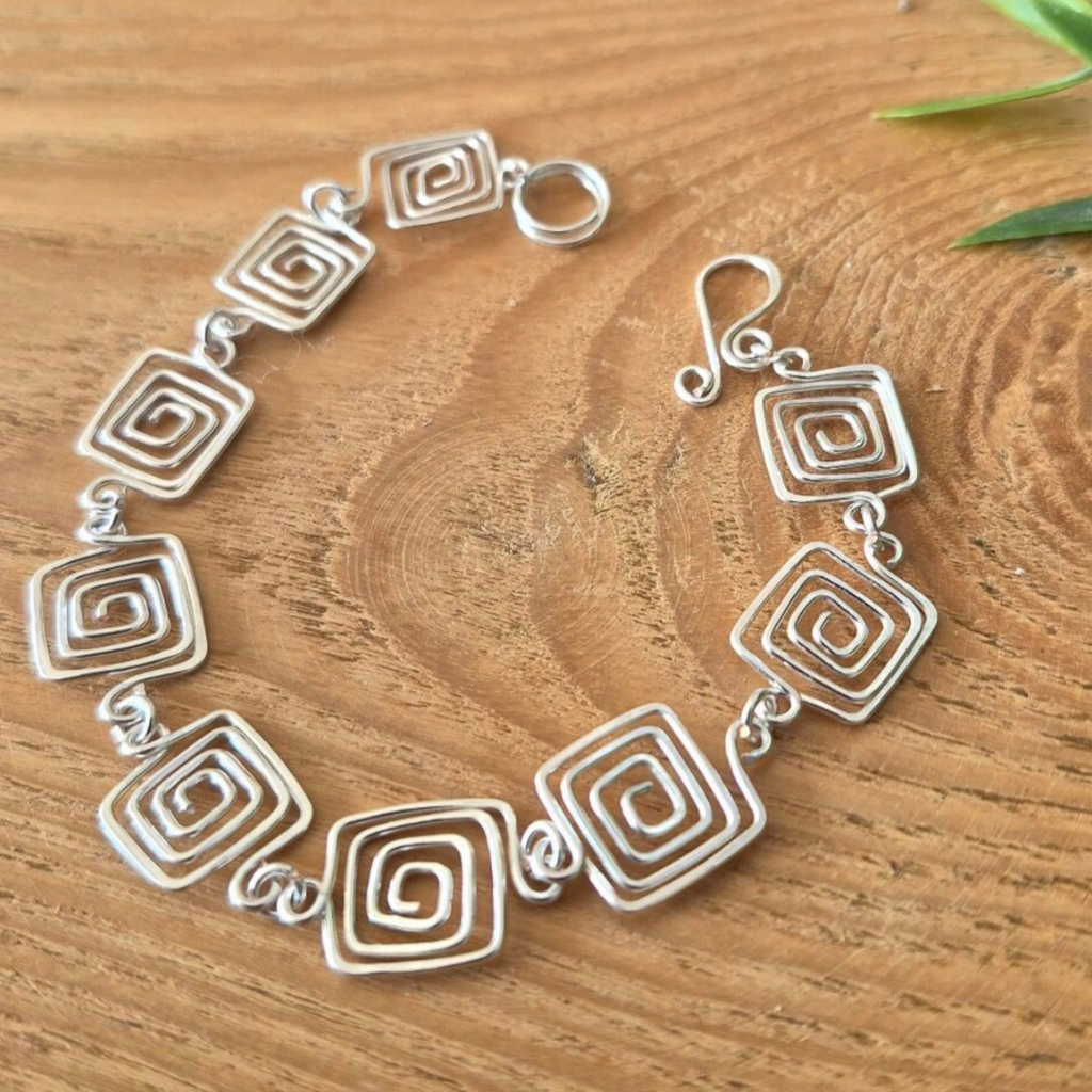 Silver bracelet with geometric design on a wooden surface