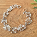 Silver bracelet with geometric design on a wooden surface