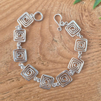 Silver bracelet with spiral designs on a wooden surface