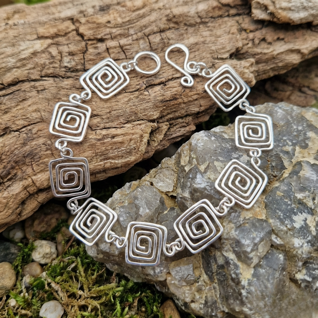 Silver bracelet with spiral designs on a natural stone background