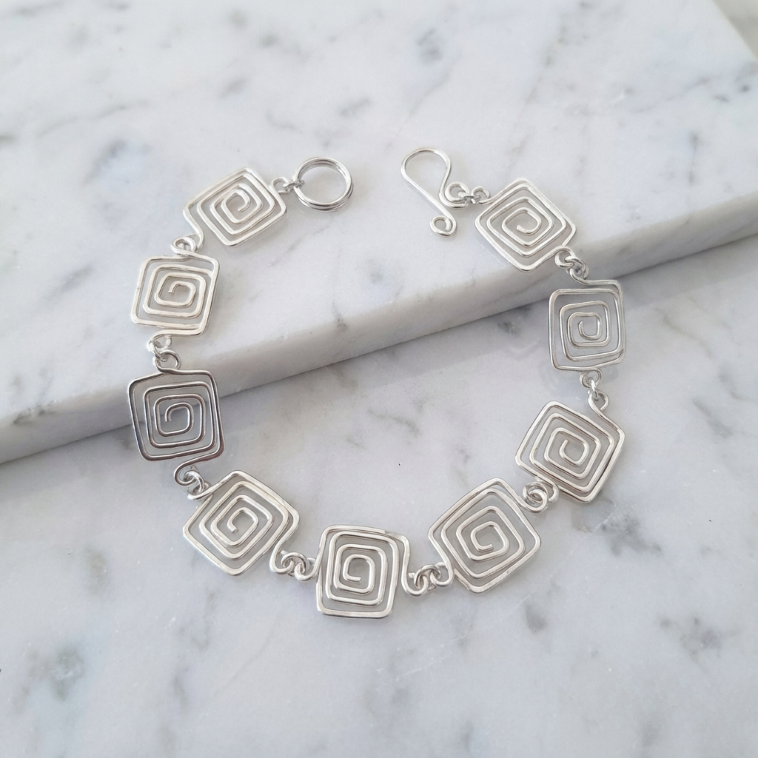 Silver bracelet with geometric design on a marble surface