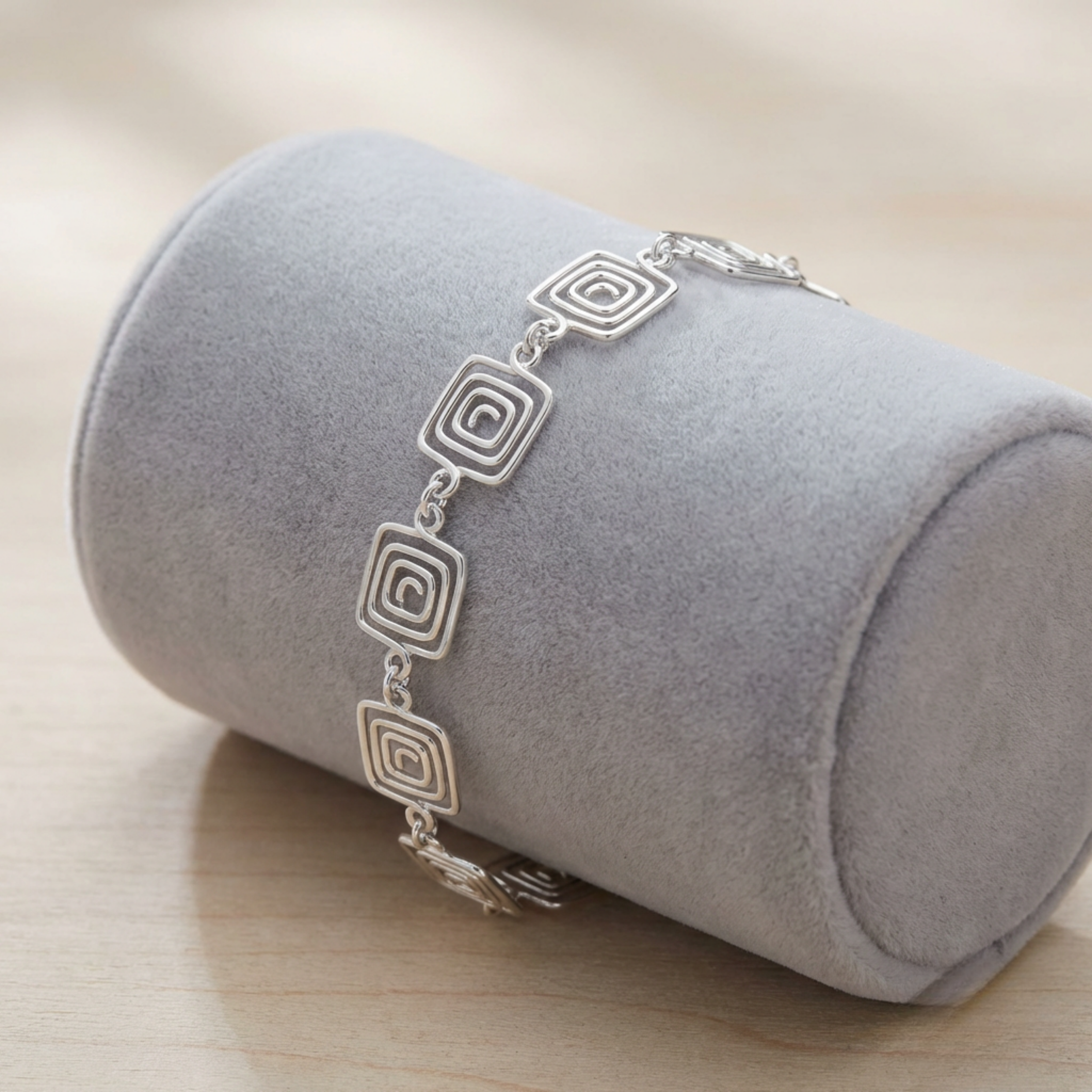 Silver bracelet with a Greek square spiral design on a grey cylindrical jewellery display