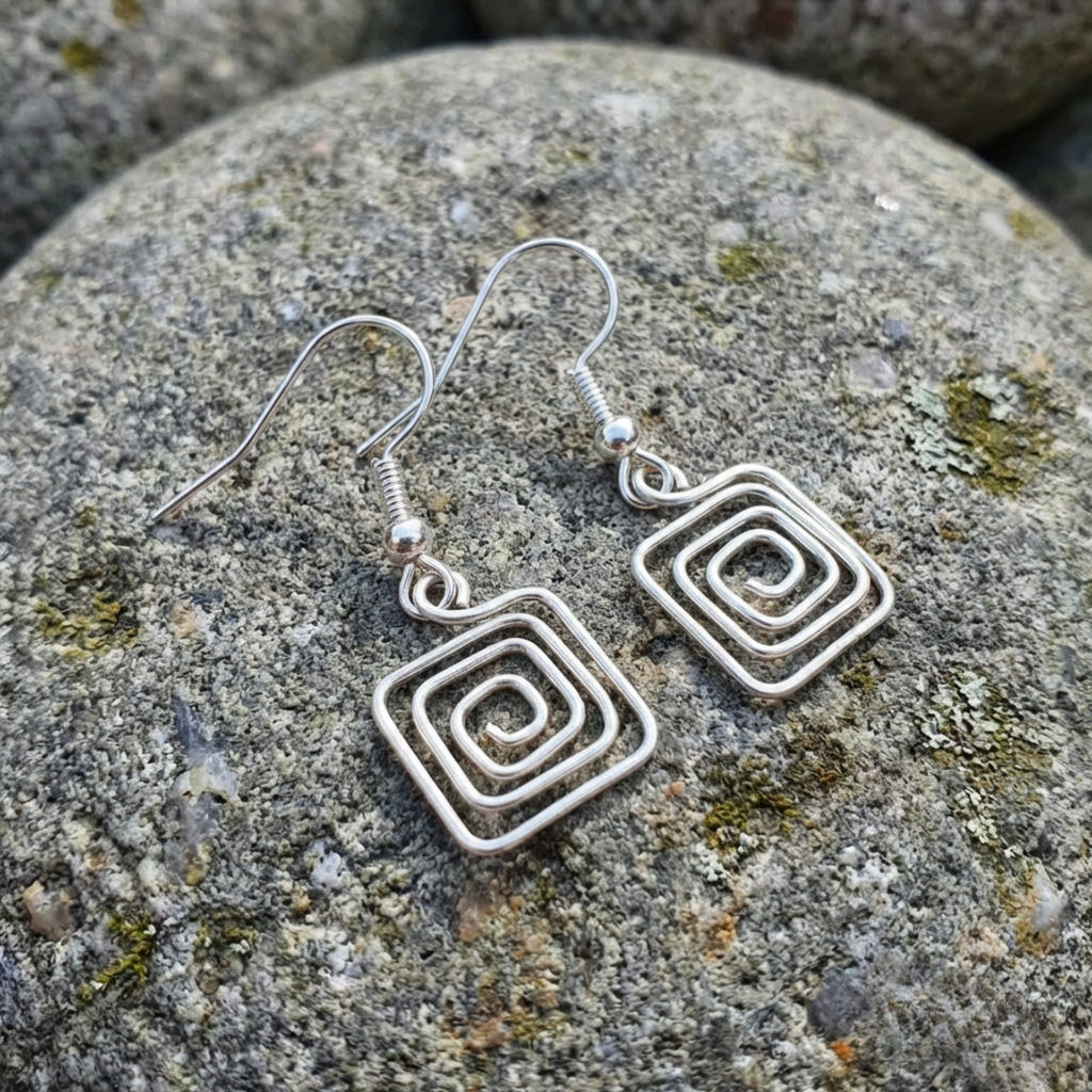 Silver spiral earrings on a stone surface