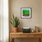 Wooden desk with potted plant, typewriter, and books against a beige wall with a framed painting.