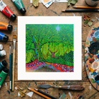 Colourful painting of a deer in a forest surrounded by art supplies on a wooden table.