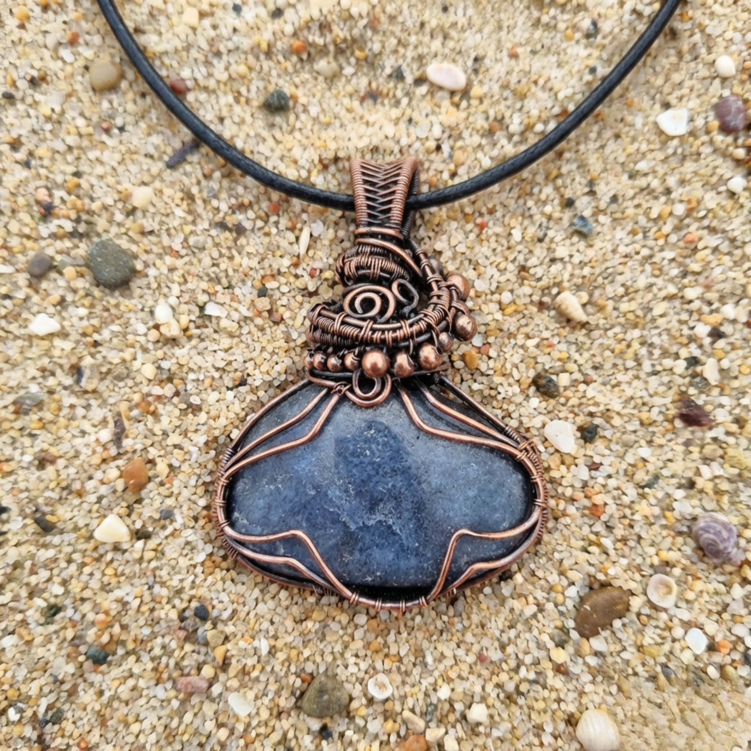 Necklace with a blue stone pendant on a sandy background