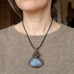 Person wearing a necklace with a blue pendant on a blurred background