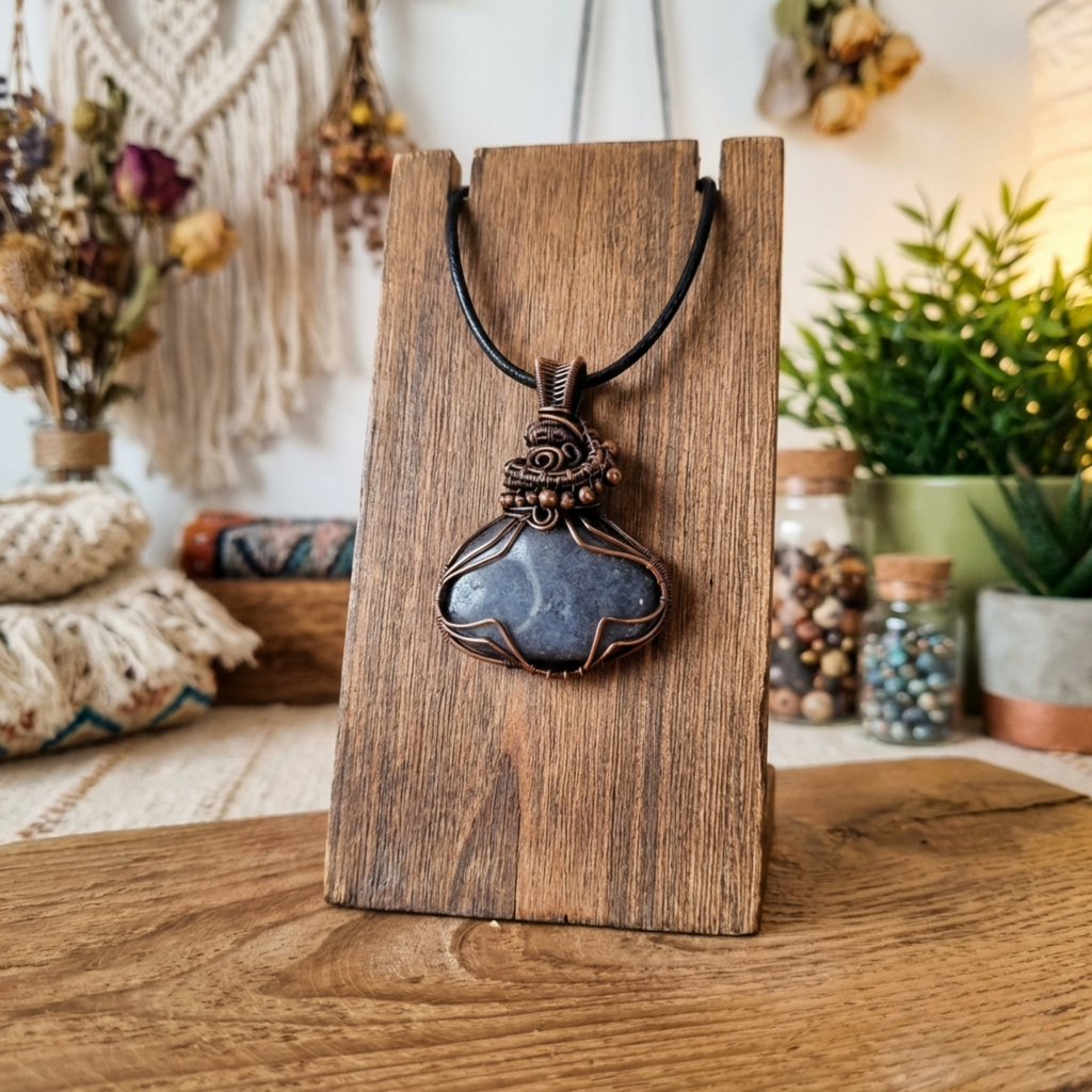 Necklace with a blue pendant on a wooden stand in a bohemian-style room.