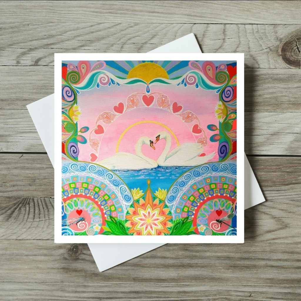 Colourful card with swan and floral design on a wooden surface