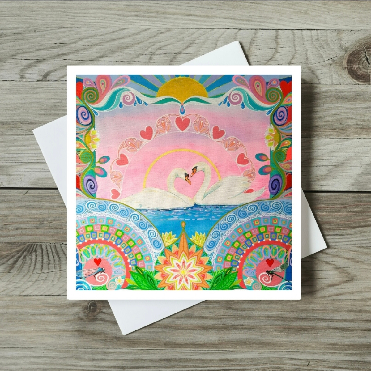 Colourful card with swan and floral design on a wooden surface