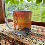 Colourful mug with artistic design on a wooden surface with a window in the background