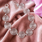 Silver spiral necklace on a pink fabric background