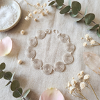 Silver spiral bracelet on a textured surface with flowers and salt.
