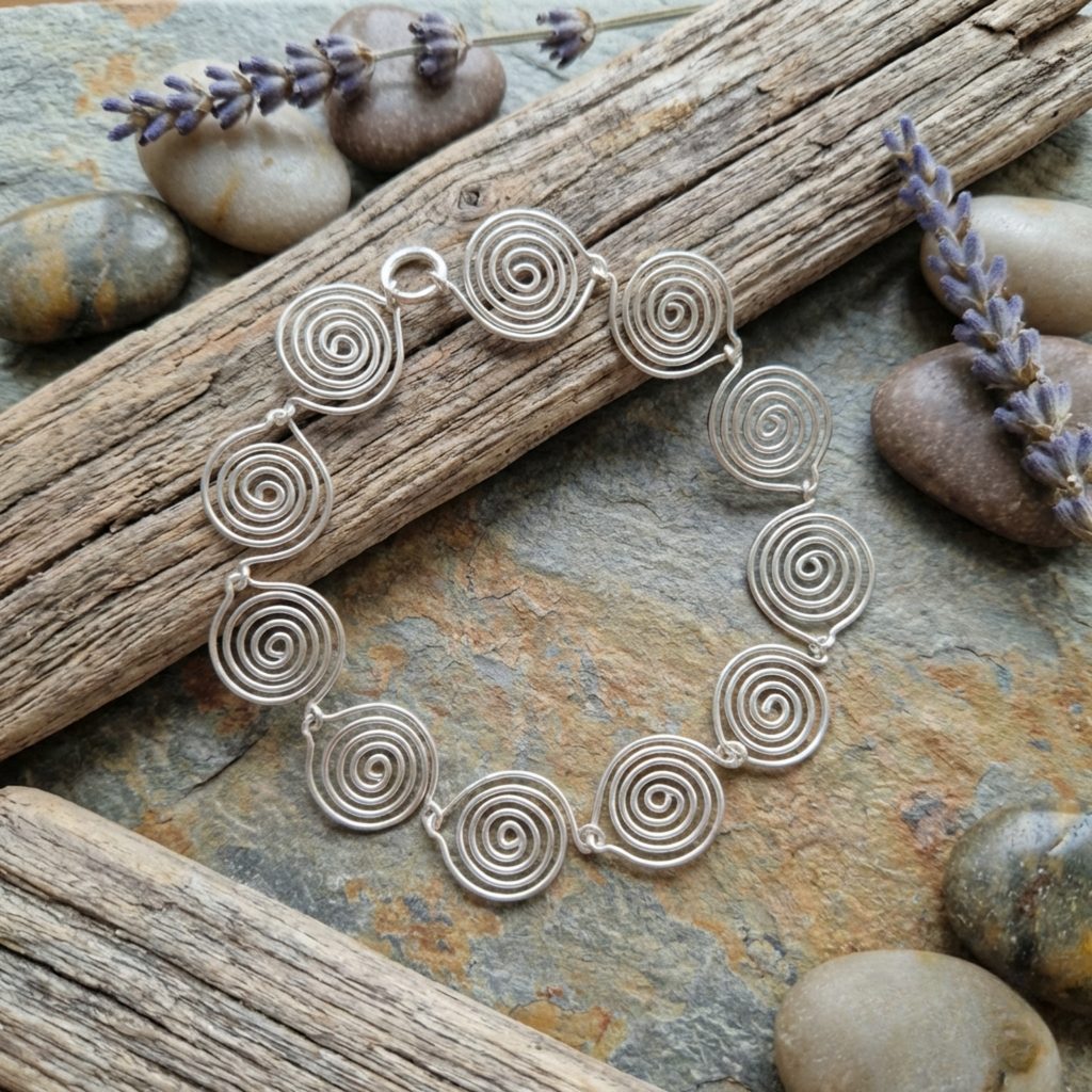 Silver spiral bracelet on a natural stone surface with lavender flowers