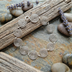Silver spiral bracelet on a natural stone surface with lavender flowers