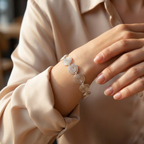 Silver bracelet with circular patterns on a wrist, wearing a beige shirt.