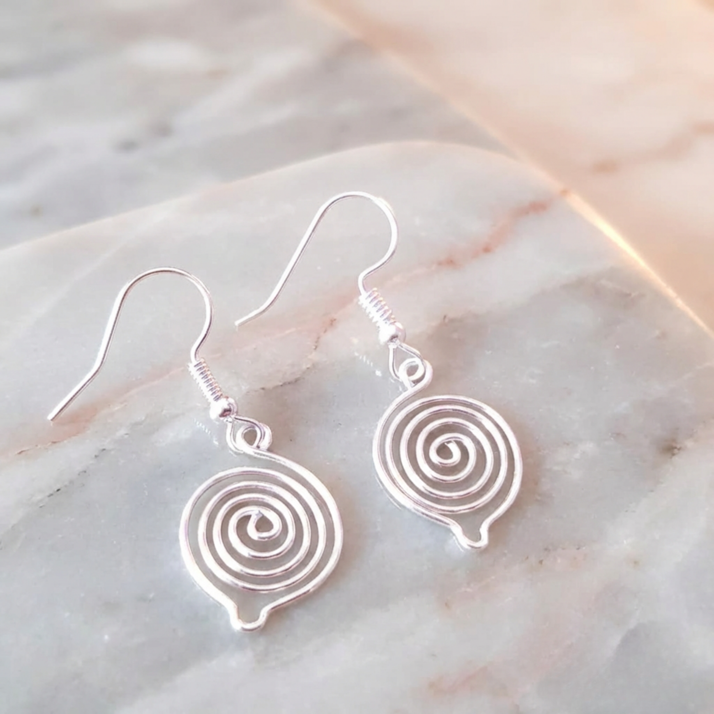 Silver spiral earrings on a marble surface