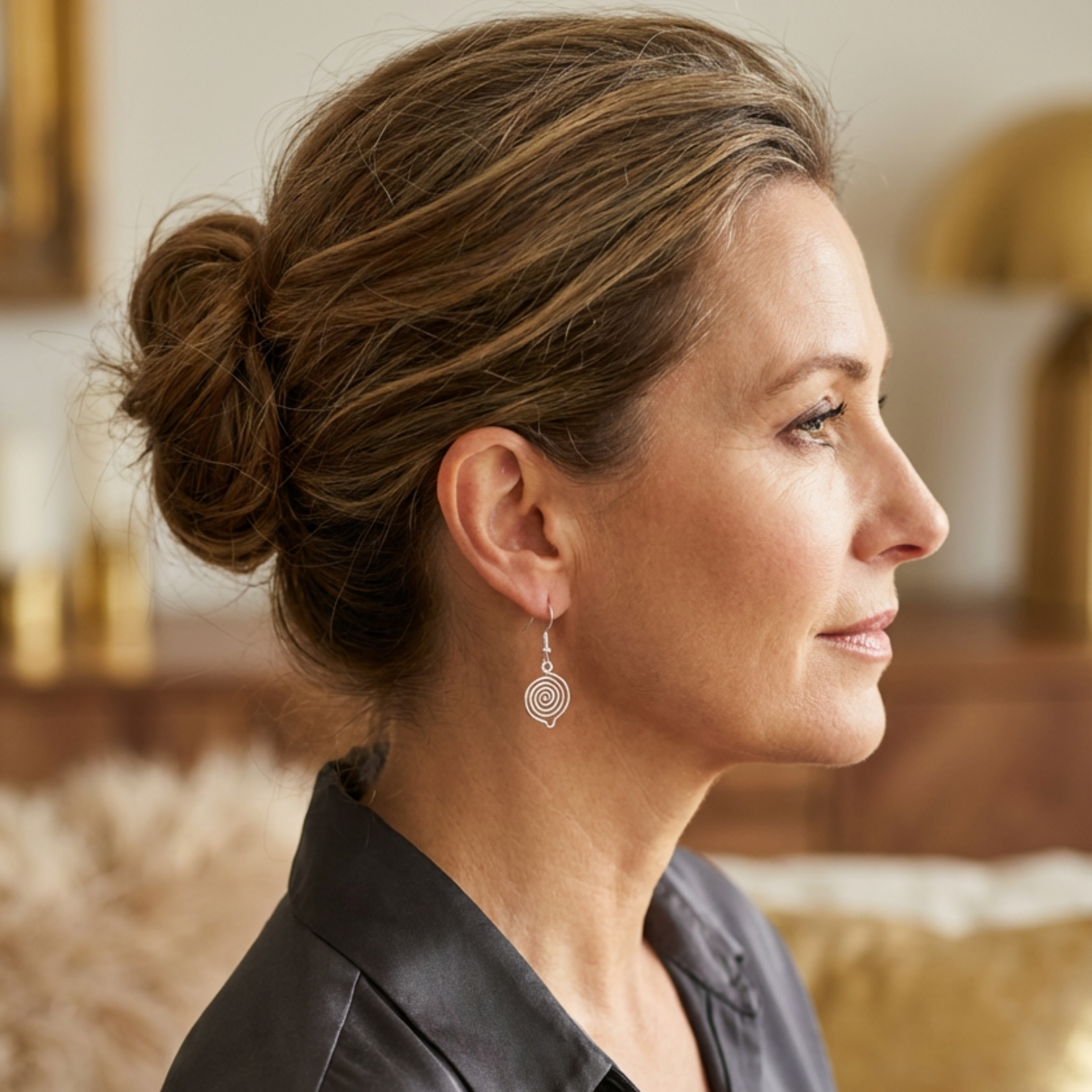 Woman with styled hair and spiral earrings in a blurred indoor setting