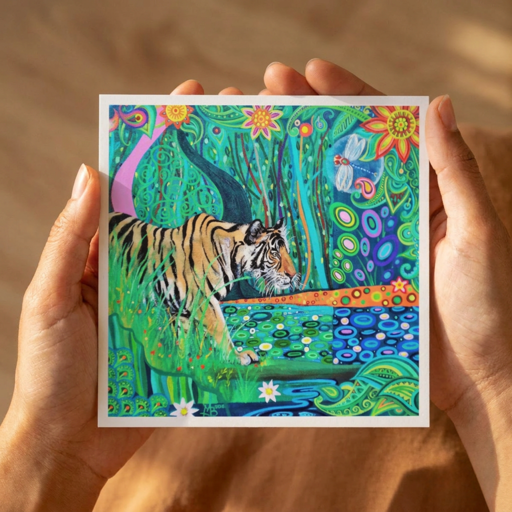 Colourful artwork of a tiger in a natural setting held by hands against a wooden background