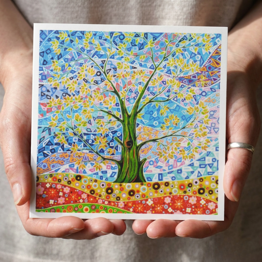 Colourful tree artwork held in hands against a neutral background