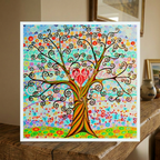 Colourful abstract tree painting with a heart at its center on a wooden surface.