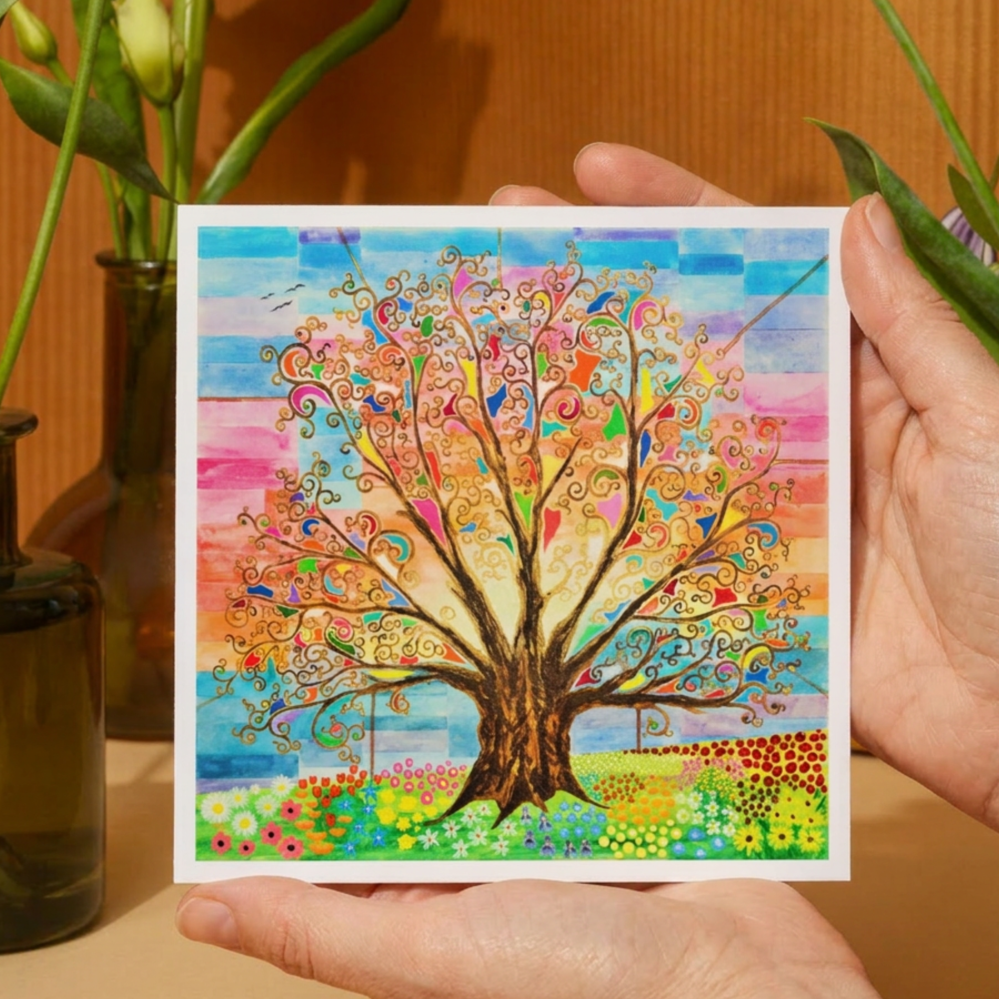 Hand holding a colorful card with a tree design against a wooden background
