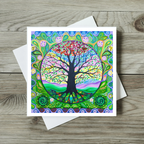 Colourful tree of life design on a card with a white envelope on a wooden surface