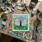 Colourful tree of life artwork on a paint-splattered table with art supplies.
