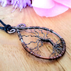 Tree of life pendant on a wooden surface with a blurred background