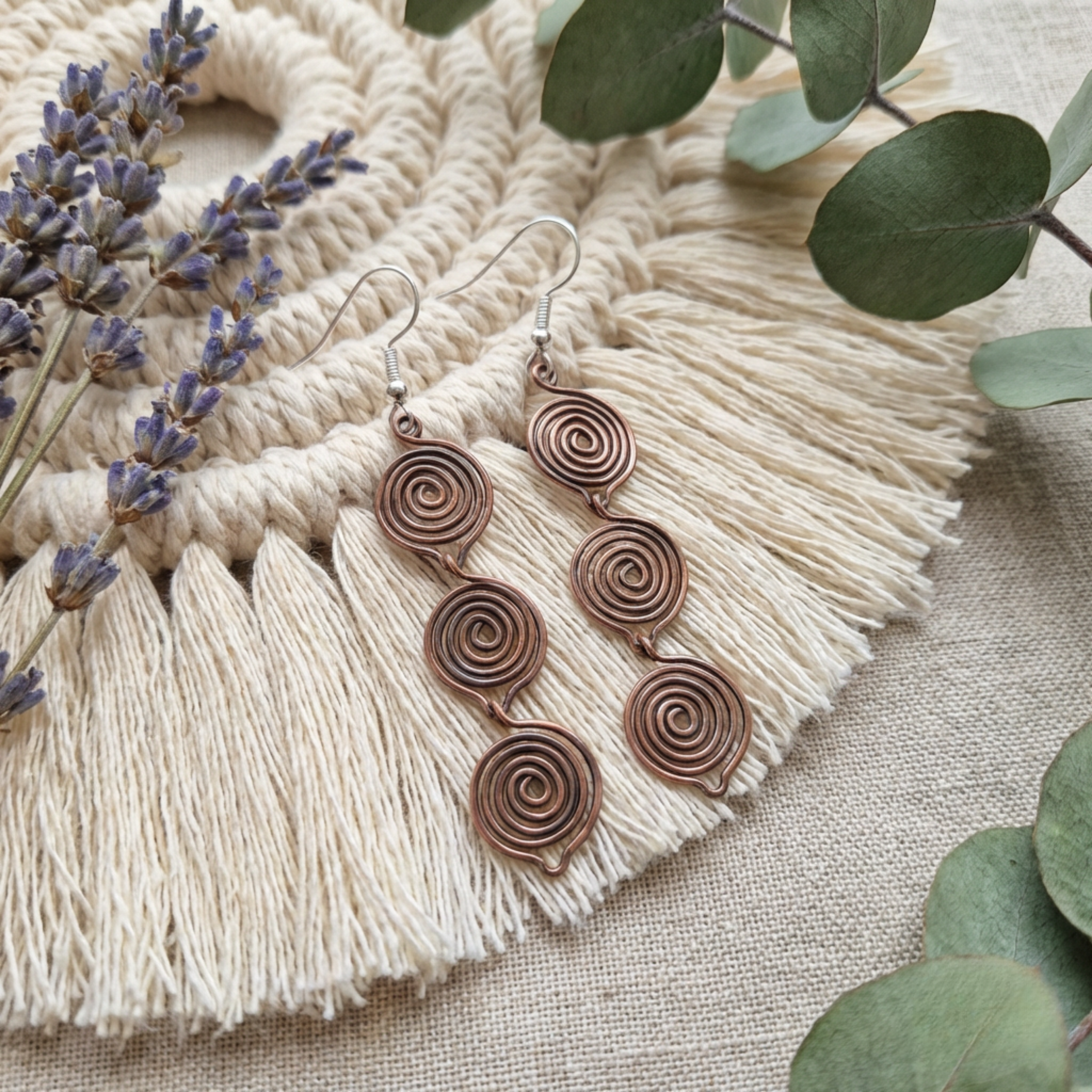 Triple teardrop copper earrings on light wood background, handmade copper jewellery UK