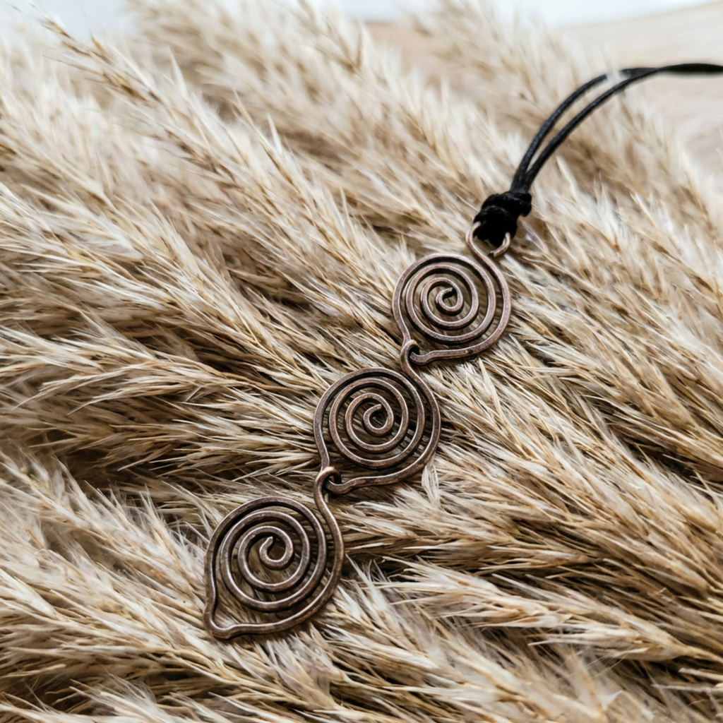 Copper spiral pendant on a black cord against a fur background