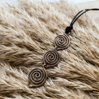 Copper spiral pendant on a black cord against a fur background