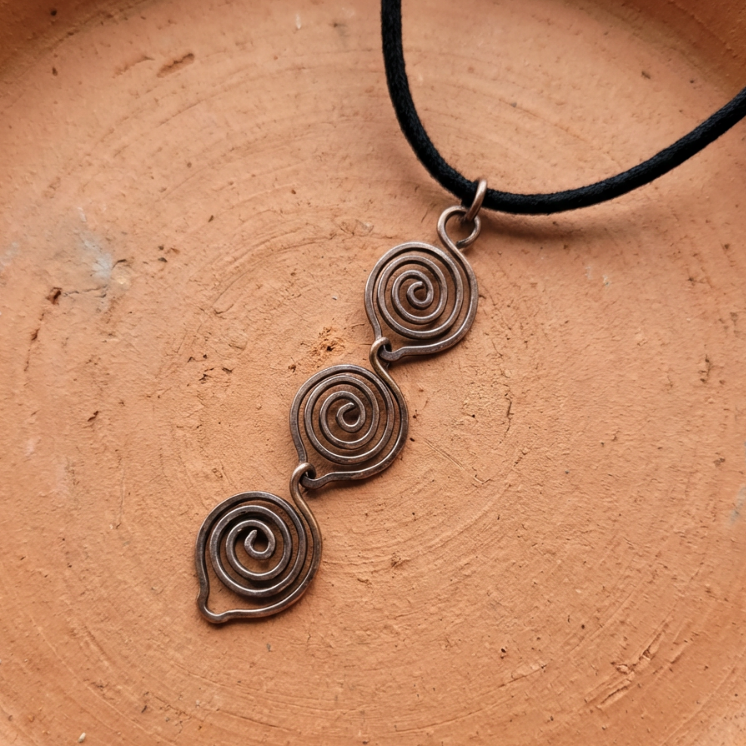 Copper spiral pendant necklace on a brown surface