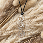 Silver spiral pendant on a black cord against a textured beige background